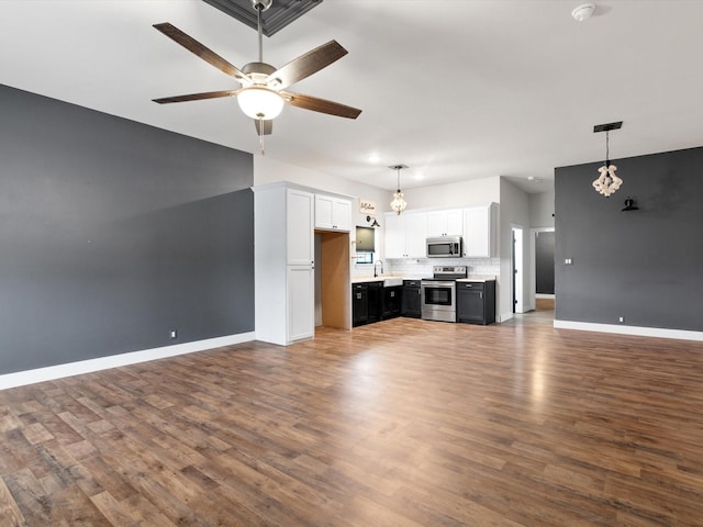 unfurnished living room featuring ceiling fan, baseboards, dark wood finished floors, and a sink