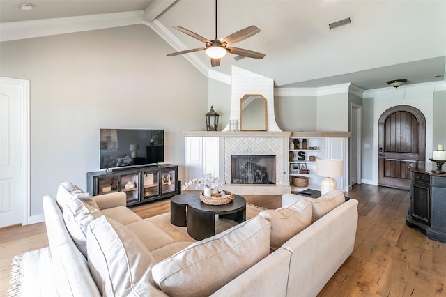 living room featuring hardwood / wood-style flooring, vaulted ceiling with beams, ceiling fan, ornamental molding, and a fireplace