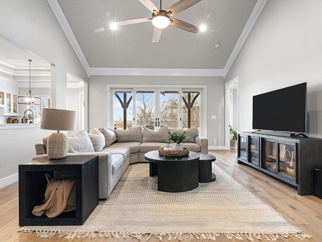 living room featuring lofted ceiling, baseboards, crown molding, and light wood finished floors