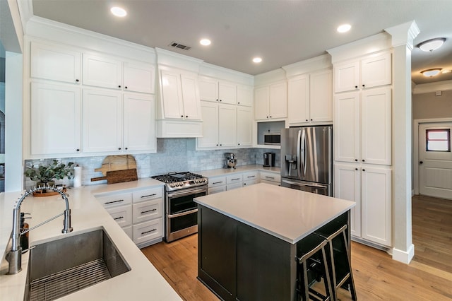 kitchen with stainless steel appliances, sink, white cabinets, a center island, and a breakfast bar area