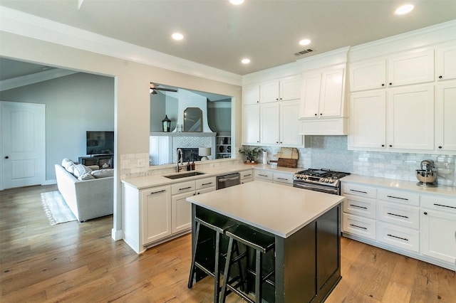 kitchen featuring kitchen peninsula, a kitchen breakfast bar, white cabinetry, and sink