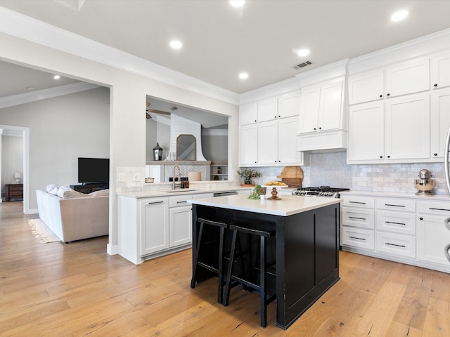 kitchen with a breakfast bar, light countertops, visible vents, white cabinetry, and a kitchen island