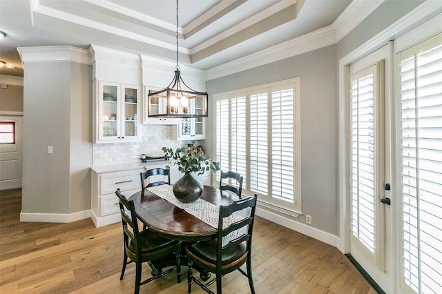 dining room featuring light wood-type flooring, a tray ceiling, and ornamental molding