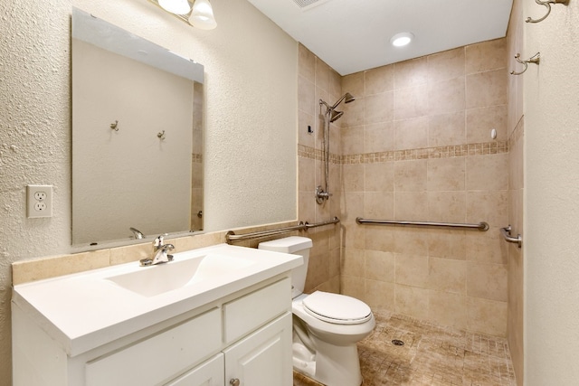 bathroom featuring toilet, oversized vanity, and tiled shower