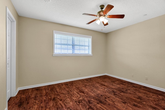 empty room featuring ceiling fan, dark wood-type flooring, and a textured ceiling