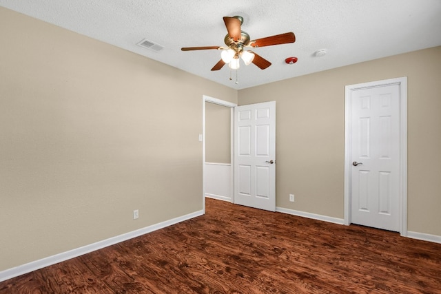 unfurnished bedroom with ceiling fan, dark wood-type flooring, and a textured ceiling