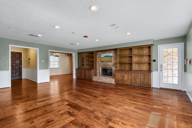 unfurnished living room with a brick fireplace, a textured ceiling, and dark hardwood / wood-style flooring