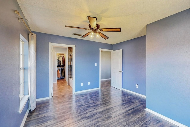 unfurnished bedroom featuring ceiling fan, dark hardwood / wood-style floors, and a textured ceiling