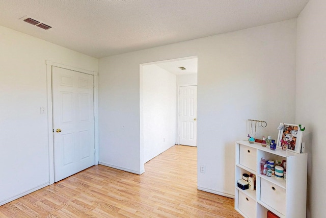 unfurnished bedroom with light hardwood / wood-style floors and a textured ceiling