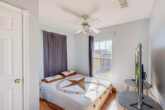 bedroom with ceiling fan, a textured ceiling, and light wood-type flooring