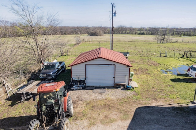 view of yard featuring a garage, an outbuilding, and a rural view