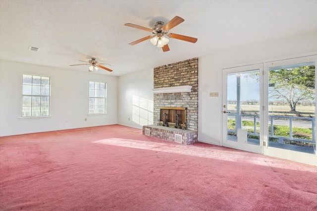 unfurnished living room featuring a brick fireplace, a healthy amount of sunlight, ceiling fan, and light colored carpet