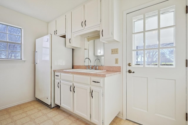 kitchen with a healthy amount of sunlight, light tile floors, and white cabinetry