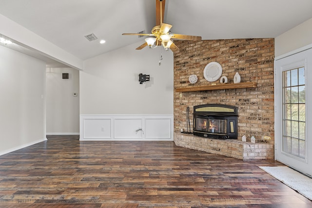 unfurnished living room with a wood stove, ceiling fan, a brick fireplace, wood-type flooring, and lofted ceiling with beams