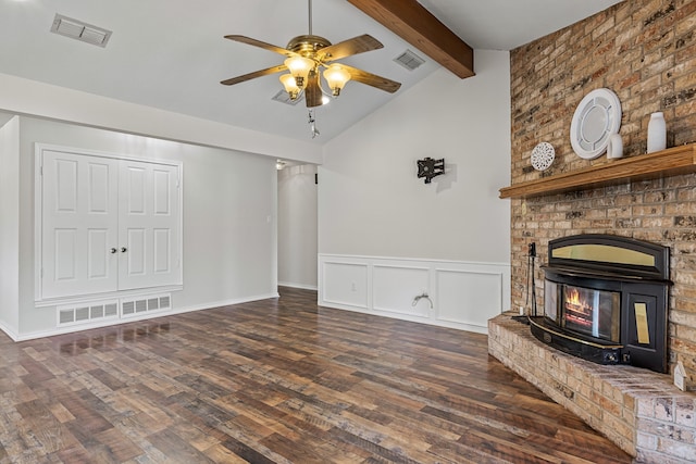 unfurnished living room with a wood stove, a fireplace, hardwood / wood-style flooring, and vaulted ceiling with beams