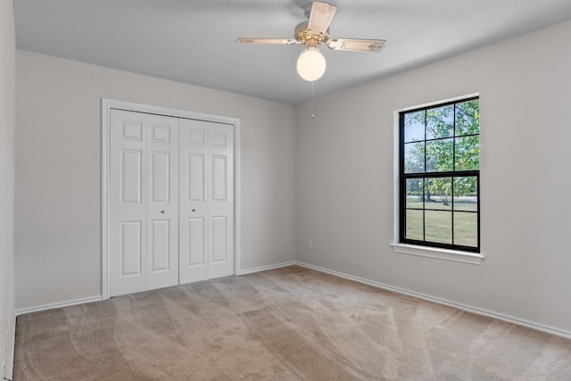 unfurnished bedroom featuring a closet, ceiling fan, and light colored carpet