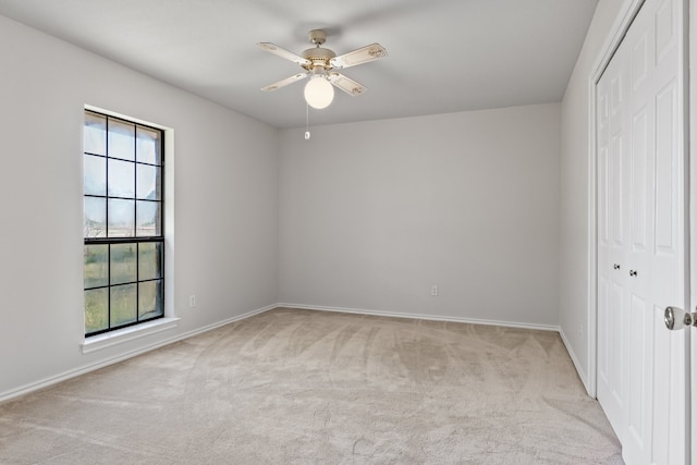 unfurnished bedroom with a closet, light carpet, multiple windows, and ceiling fan