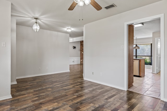 empty room featuring brick wall, ceiling fan, and dark hardwood / wood-style floors