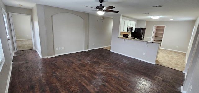 unfurnished living room featuring ceiling fan and dark wood-type flooring