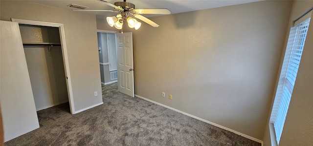 unfurnished bedroom featuring ceiling fan, dark carpet, and a closet