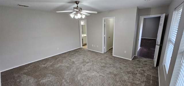 unfurnished bedroom with ensuite bathroom, ceiling fan, and dark colored carpet