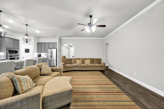 living room featuring crown molding, dark wood-type flooring, and ceiling fan with notable chandelier