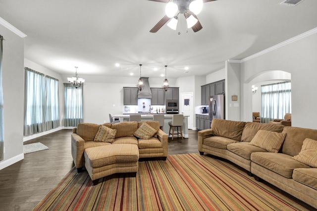 living room featuring crown molding, ceiling fan with notable chandelier, and dark wood-type flooring