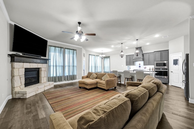 living room featuring a fireplace, ornamental molding, dark hardwood / wood-style floors, and ceiling fan with notable chandelier