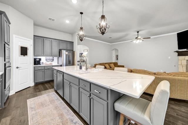 kitchen featuring a center island with sink, dark hardwood / wood-style flooring, appliances with stainless steel finishes, and ceiling fan with notable chandelier