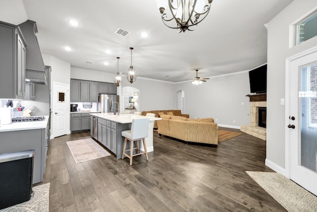 kitchen with dark hardwood / wood-style floors, an island with sink, gray cabinets, a breakfast bar, and ceiling fan with notable chandelier