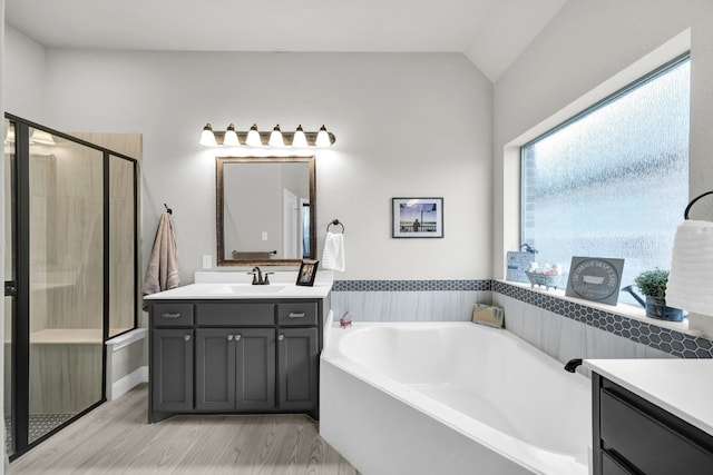 bathroom with hardwood / wood-style floors, independent shower and bath, vaulted ceiling, and large vanity