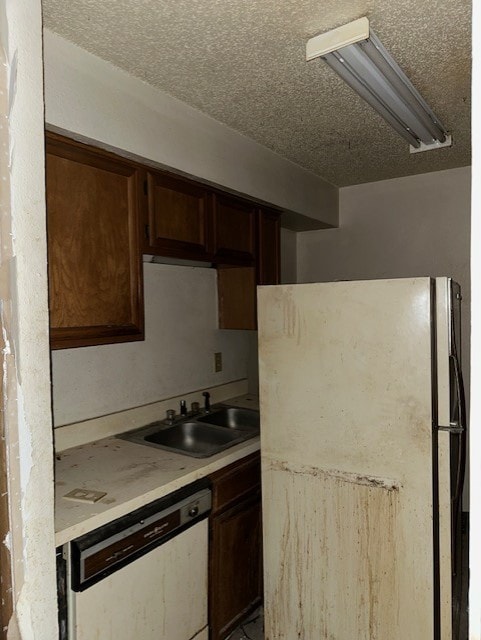 kitchen featuring a textured ceiling, dishwasher, sink, and fridge