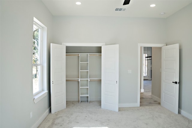 unfurnished bedroom with multiple windows, light carpet, ceiling fan, and a closet