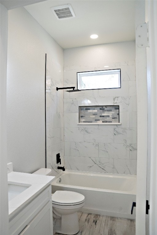 full bathroom with tiled shower / bath, hardwood / wood-style floors, vanity, and toilet