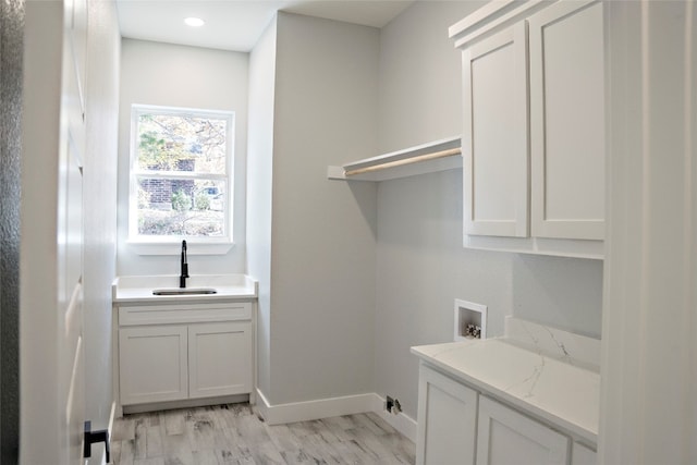 laundry area featuring hookup for a washing machine, sink, cabinets, and light hardwood / wood-style floors