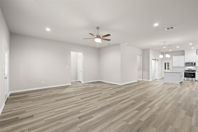 unfurnished living room with ceiling fan with notable chandelier and light hardwood / wood-style flooring