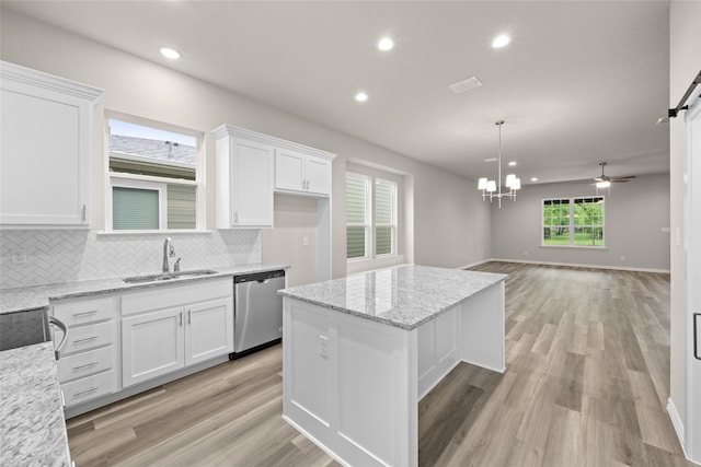 kitchen with dishwasher, white cabinetry, light stone counters, and sink