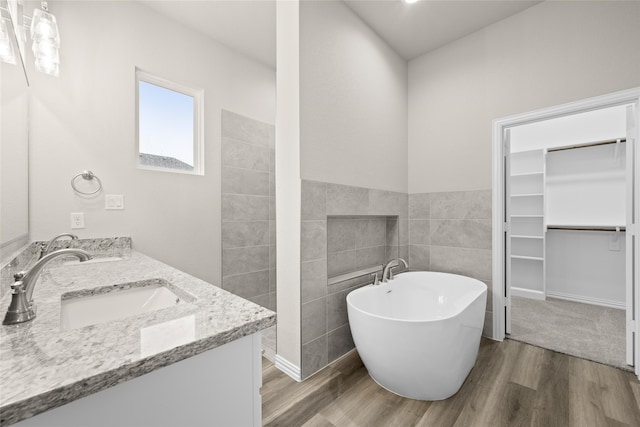 bathroom with a bathtub, tile walls, vanity, and hardwood / wood-style flooring