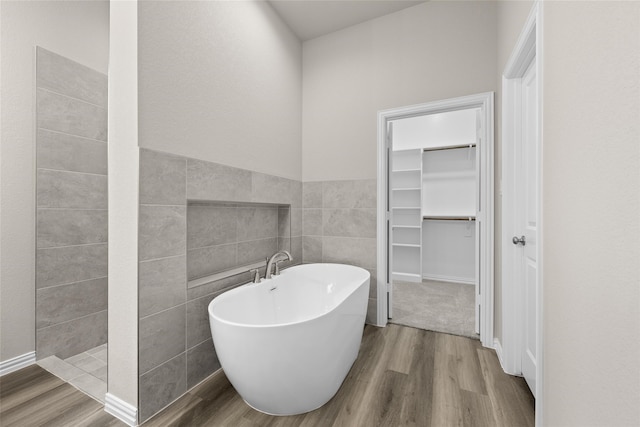 bathroom with independent shower and bath, tile walls, and hardwood / wood-style flooring