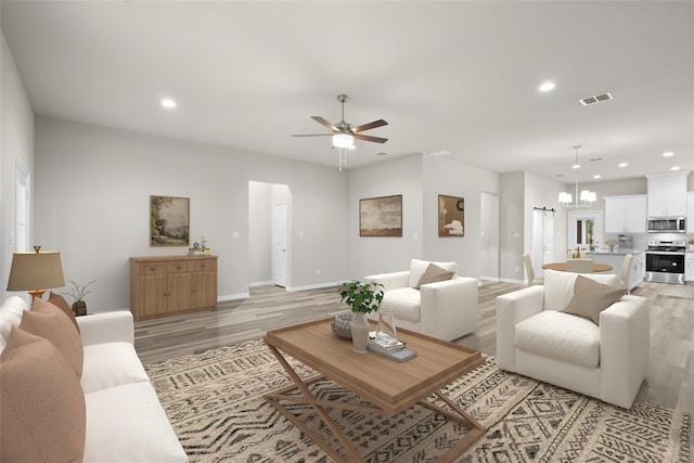 living room with ceiling fan with notable chandelier and light wood-type flooring