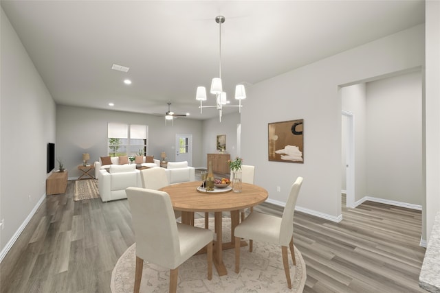 dining area with wood-type flooring and ceiling fan with notable chandelier