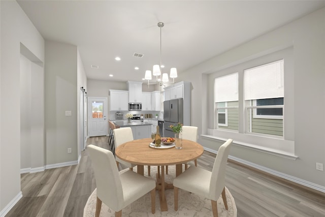 dining area featuring an inviting chandelier, a wealth of natural light, and light hardwood / wood-style floors