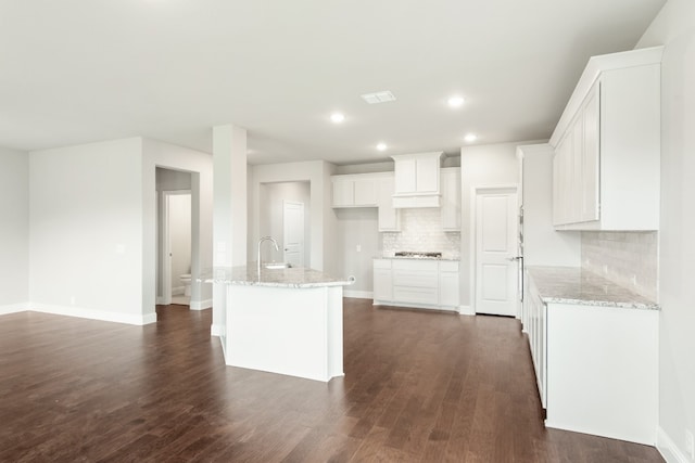 kitchen with sink, tasteful backsplash, white cabinetry, dark hardwood / wood-style floors, and light stone countertops