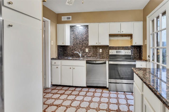 kitchen with dark stone countertops, light tile floors, appliances with stainless steel finishes, and sink