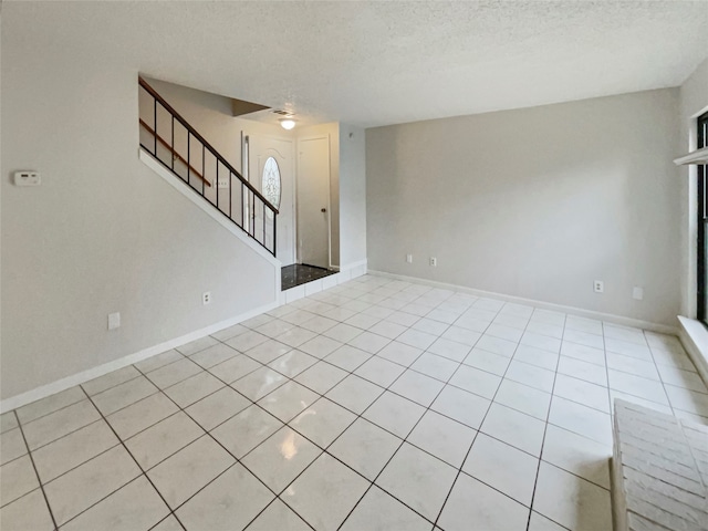 tiled empty room featuring a textured ceiling