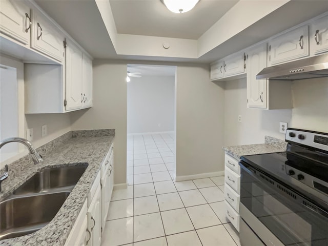 kitchen with stainless steel electric range, sink, light tile patterned floors, white cabinetry, and a tray ceiling