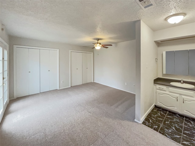 interior space with vanity, tile patterned flooring, ceiling fan, and a textured ceiling