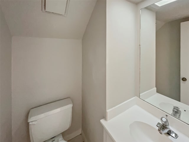 bathroom featuring vaulted ceiling, toilet, and sink