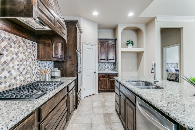 kitchen with sink, decorative backsplash, stainless steel appliances, dark brown cabinetry, and light stone countertops