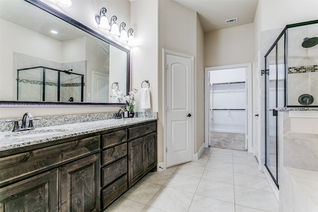 bathroom with walk in shower, vanity, and tile patterned flooring